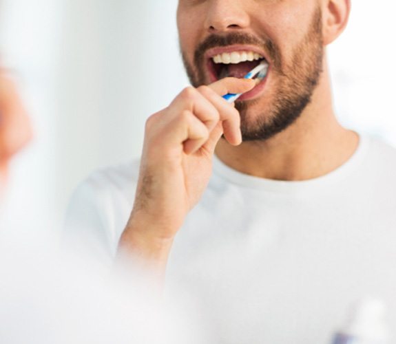 Man looking in mirror and brushing his teeth